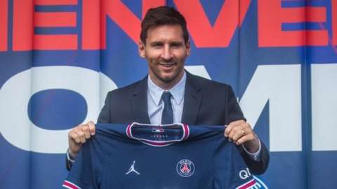 Lionel Messi holds his new Paris St-Germain jersey