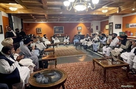 Former Afghan President Hamid Karzai, accompanied by the old government's main peace envoy, Abdullah Abdullah, sits for talks with members of the Taliban delegation in this undated handout, Aug. 19, 2021.