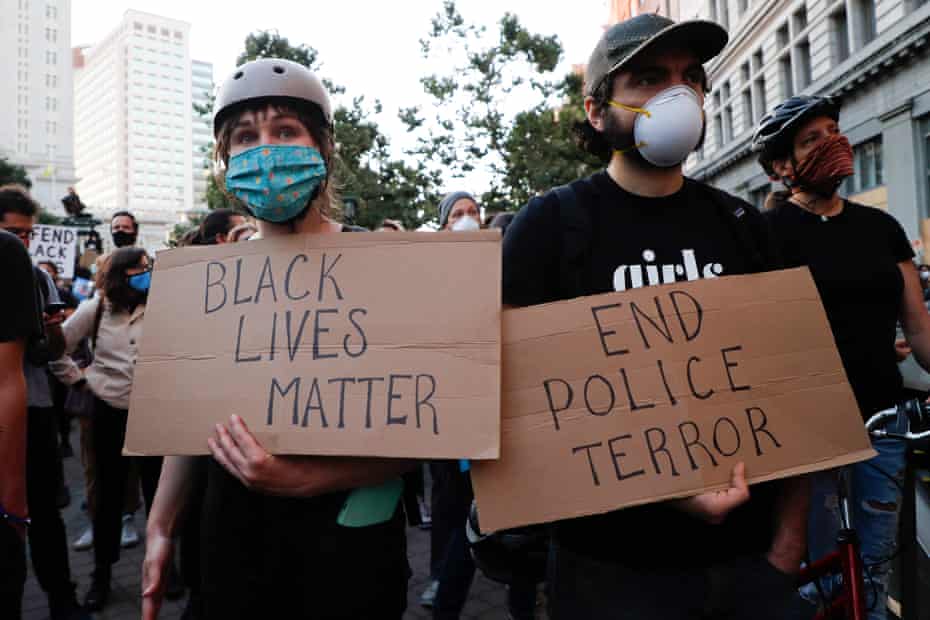 People hold signs reading “Black Lives Matter” and “End police terror” during a protest in Oakland, California, on 3 June 2020.