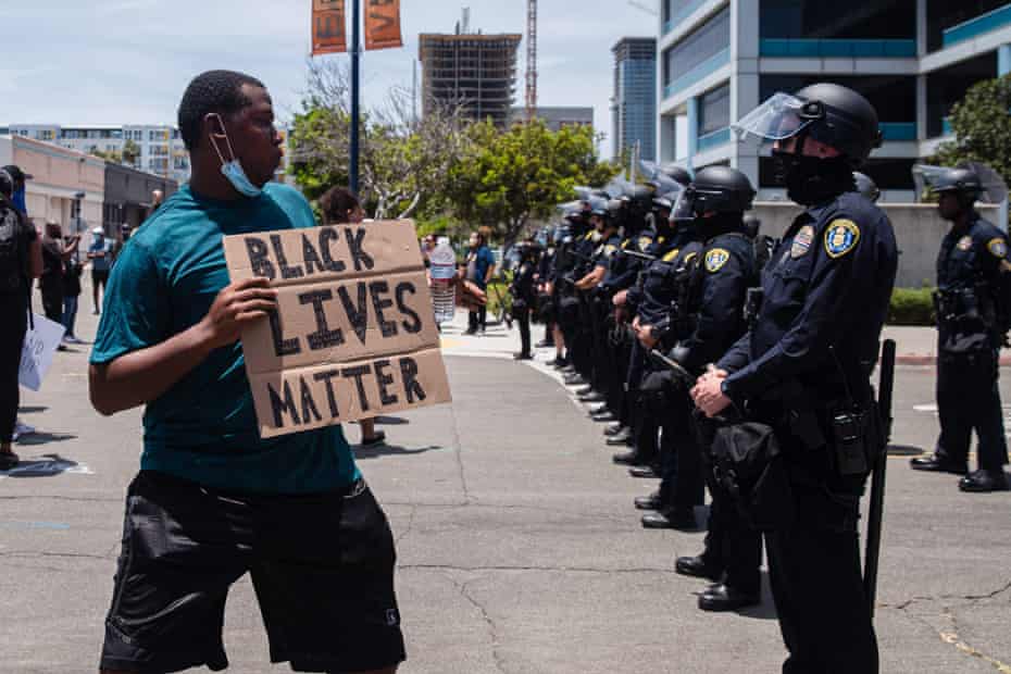 A man holds a Black Lives Matter sign in front of a line of San Diego police officers on 31 May 2020.