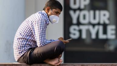 A man wearing a facemask as a preventive measure against the Covid-19 coronavirus checks his mobile phone in New Delhi on November 20, 2020.