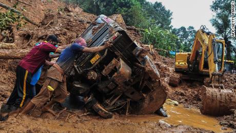 Rescue workers push a overturned vehicle stuck in the mud and debris at a site of a landslide claimed to be caused by heavy rains in Kokkayar in India&#39;s Kerala state on October 17, 2021.