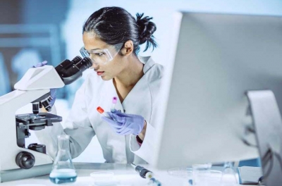 female researcher using a microscope in a lab