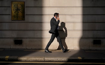 A man talks on his phone as he walks through the City of London