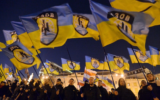 Ukrainian nationalists and servicemen of the Azov battalion wave flags in Kiev on October 14, 2014, during a march to mark the founding of the Ukrainian Insurgent Army
