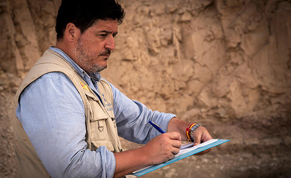 Professor Antonio Morales writing on a clipboard visiting an archaeological site
