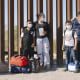 Image: Asylum seekers wait to be processed by the Customs and Border Protection, next to the border wall between Mexico and the U.S in Yuma, Arizona.