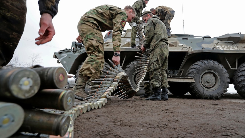 Service members of pro-Russian troops load ammunition into an armoured personnel carrier.
