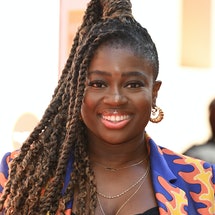 Clara Amfo wearing a purple, orange and yellow patterned suit jacket. Her hair is in braids and a po...