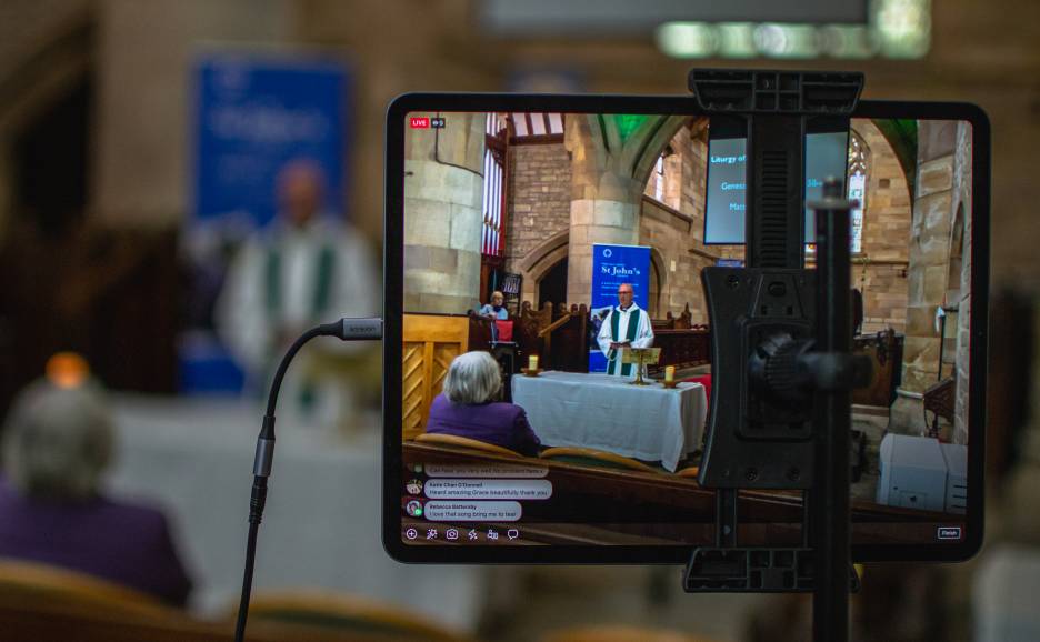 Tablet showing the live stream of a priest leading a church service