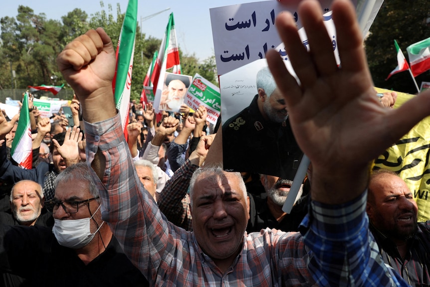 Demonstrators hold up Iranian flags and images of clerics.
