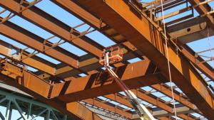 Thumbnail image of worker on a crane beneath girders of the new Sellwood Bridge.