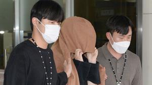 A woman with her head covered leaves the Seoul Central District Prosecutors' Office at Ulsan Jungbu police station in Ulsan, South Korea. AP