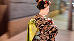 A maiko, or apprentice geisha, walks between teahouses in Gion, Kyoto