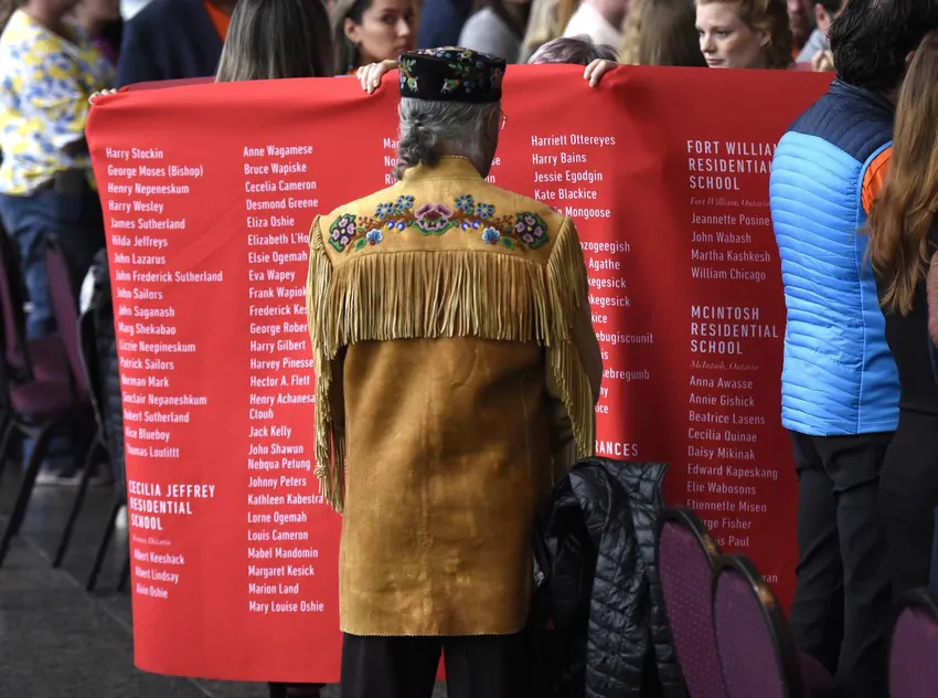 Clement Chartier, president of the Metis National Council, watches as a ceremonial cloth with the names of 2,800 children who died in residential schools and were identified in the National Student Memorial Register, is carried to the stage during Monday's ceremony.