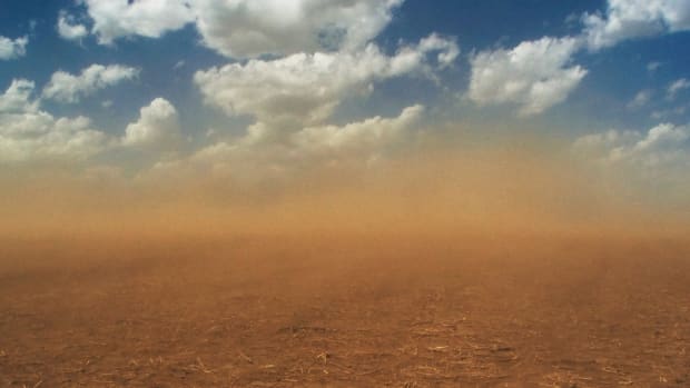 A dust storm roars across an empty field.