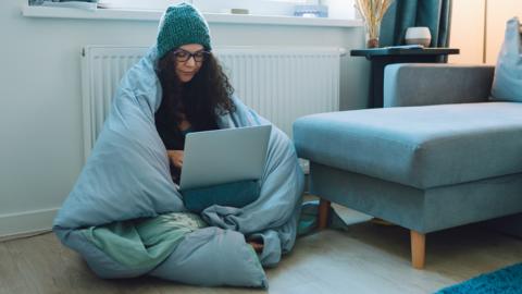 Person wrapped in blanket on laptop