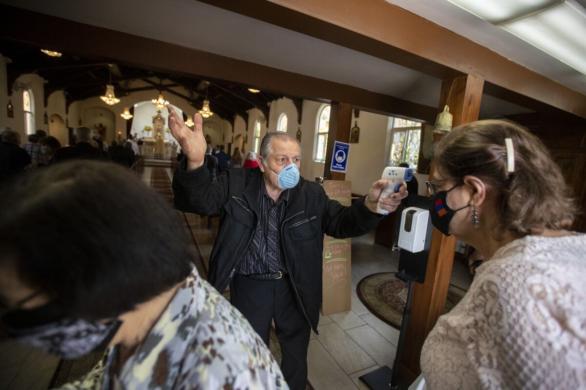 Usher Antoine Soumakian takes parishioners' temperatures as they file in for Sunday service