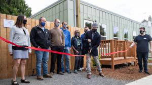 Partners in supporting the St. Johns Village watch Do Good Multnomah director Chris Aiosa cut a ceremonial ribbon on May 21, 2021.