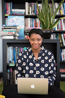 Black woman with laptop sitting in front of a bookcase