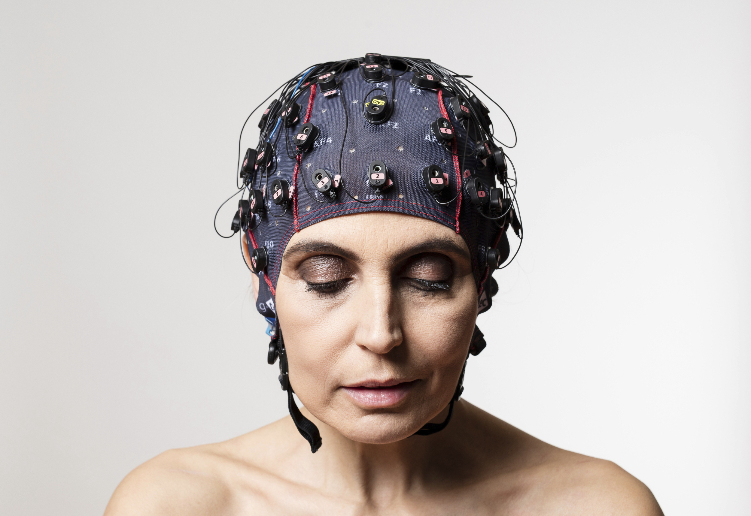 A woman equipped with a brain-computer interface that she is wearing as a bathing-suit-style cap on her head.
