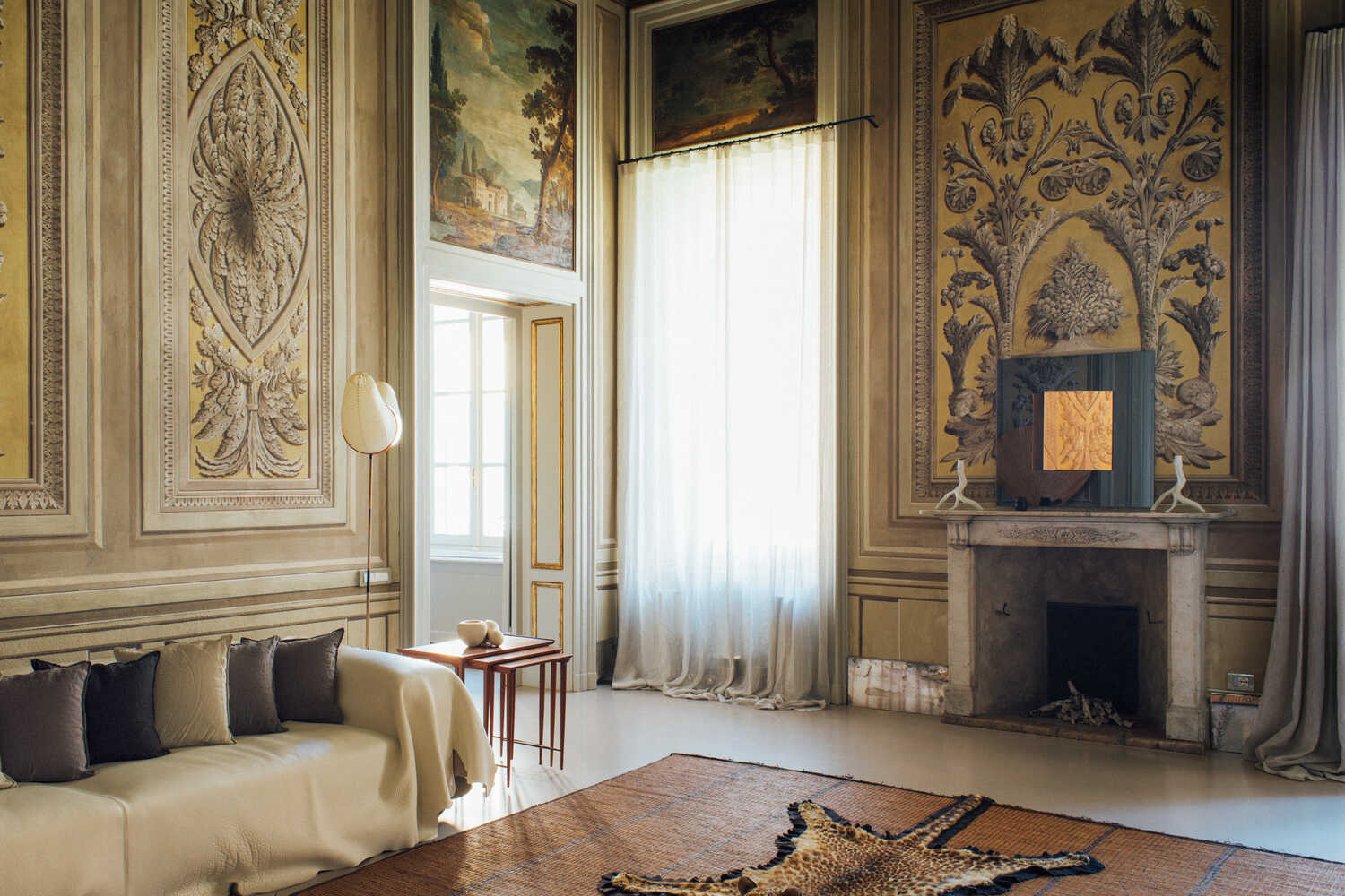 In a salon of an apartment in Brescia, Italy, renovated by the designer Paola Moretti, Pompeiian-style friezes, a leather-draped Edra Gran Khan sofa, an Akari lamp by Isamu Noguchi and a leopard skin rug made in 1935 by the Indian taxidermy firm Van Ingen & Van Ingen, atop a vintage Tuareg mat.