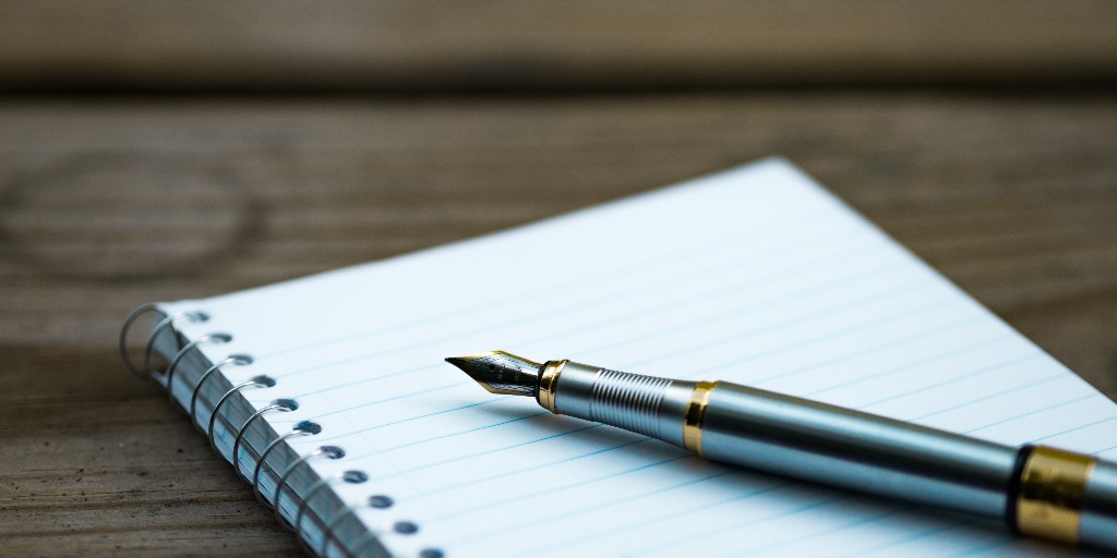 Stock image shows a pen sat on a blank notebook.