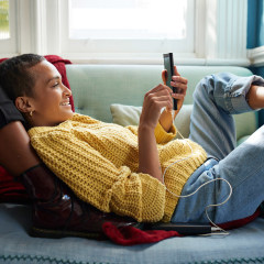 Woman relaxing on her couch with her partner while listening to music and playing on her phone
