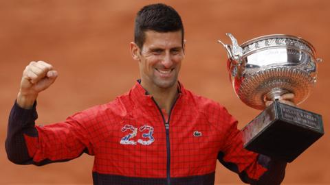 Novak Djokovic with the number 23 embroidered on his top - the number of Grand Slams he has now won - and the French Open trophy