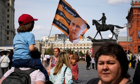 A child sits on his father's shoulders and a pro-Kremlin activist waves a flag bearing the face of Putin