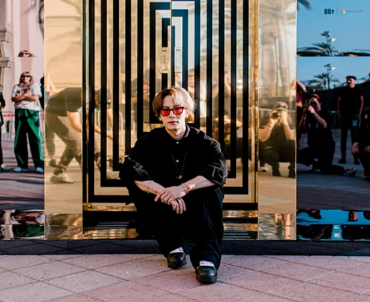 Singer, Jackson Wang, sits in front of the reflective elevator doors that welcome attendees to his show, The Magic Man Experience.