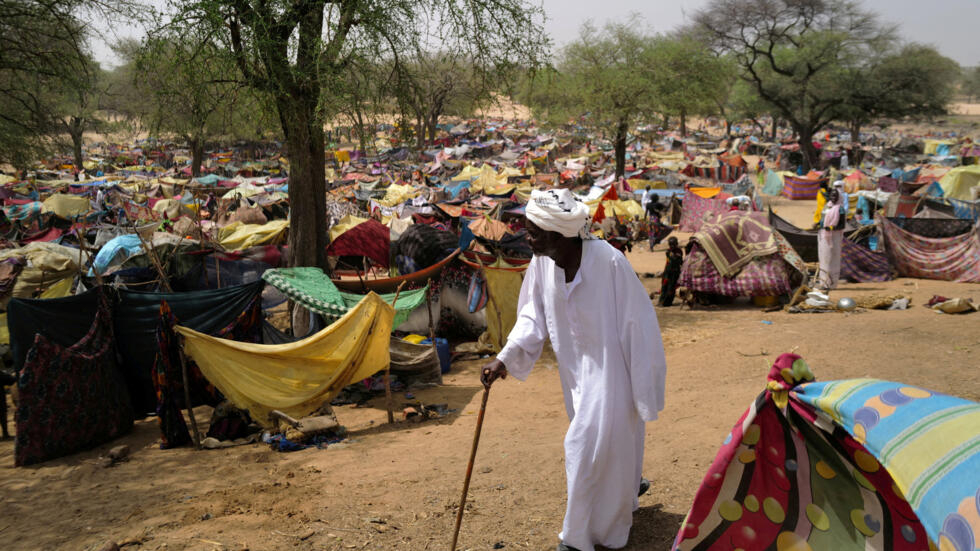 A Sudanese men who fled the conflict in Sudan's Darfur region, and was previously internally displaced in Sudan, walks past makeshift shelters near the border between Sudan and Chad, while taking refuge in Borota, Chad, May 13, 2023. 