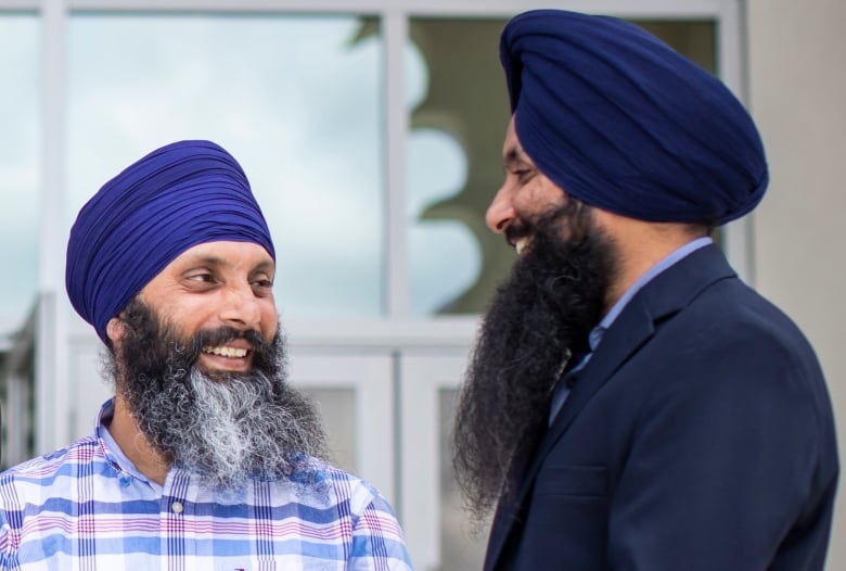 A group of Sikh men speak informally to each other for a posed photograph.