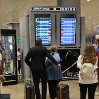 Passengers look at a departure board at Ben Gurion Airport near Tel Aviv, as flights are canceled and delayed because of a massive surprise attack by Hamas, on October 7, 2023. (GIL COHEN-MAGEN/AFP)
