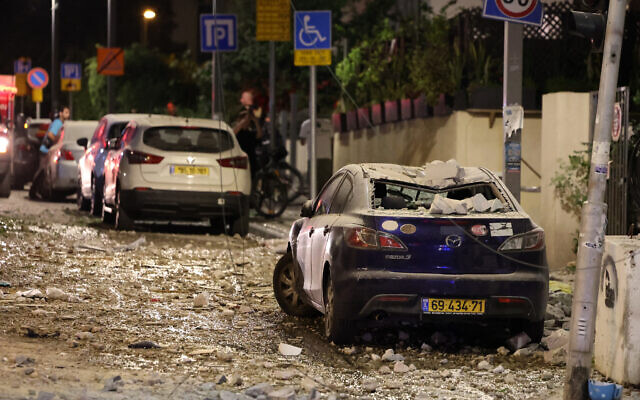 People assess damage from a Gazan rocket strike on a street in Tel Aviv on October 7, 2023. (JACK GUEZ / AFP)