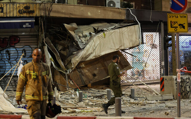 A rescuer walks in front of a damaged shop in Tel Aviv, after it was hit by a rocket fired by Palestinian terrorists from the Gaza Strip on October 7, 2023. (JACK GUEZ / AFP)
