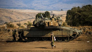An Israeli soldier walks past a tank amid heightened tensions between Israel and Lebanon, as seen from the border with Lebanon in northern Israel, October 14, 2023. (Reuters)
