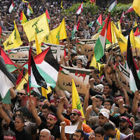 Hezbollah supporters wave Lebanese, Palestinian and their group flags, as they hold pro-Gaza placards during a protest to show their solidarity with the Palestinians, in the southern suburb of Beirut, Lebanon, Friday, Oct. 13, 2023.  (AP/Hussein Malla)