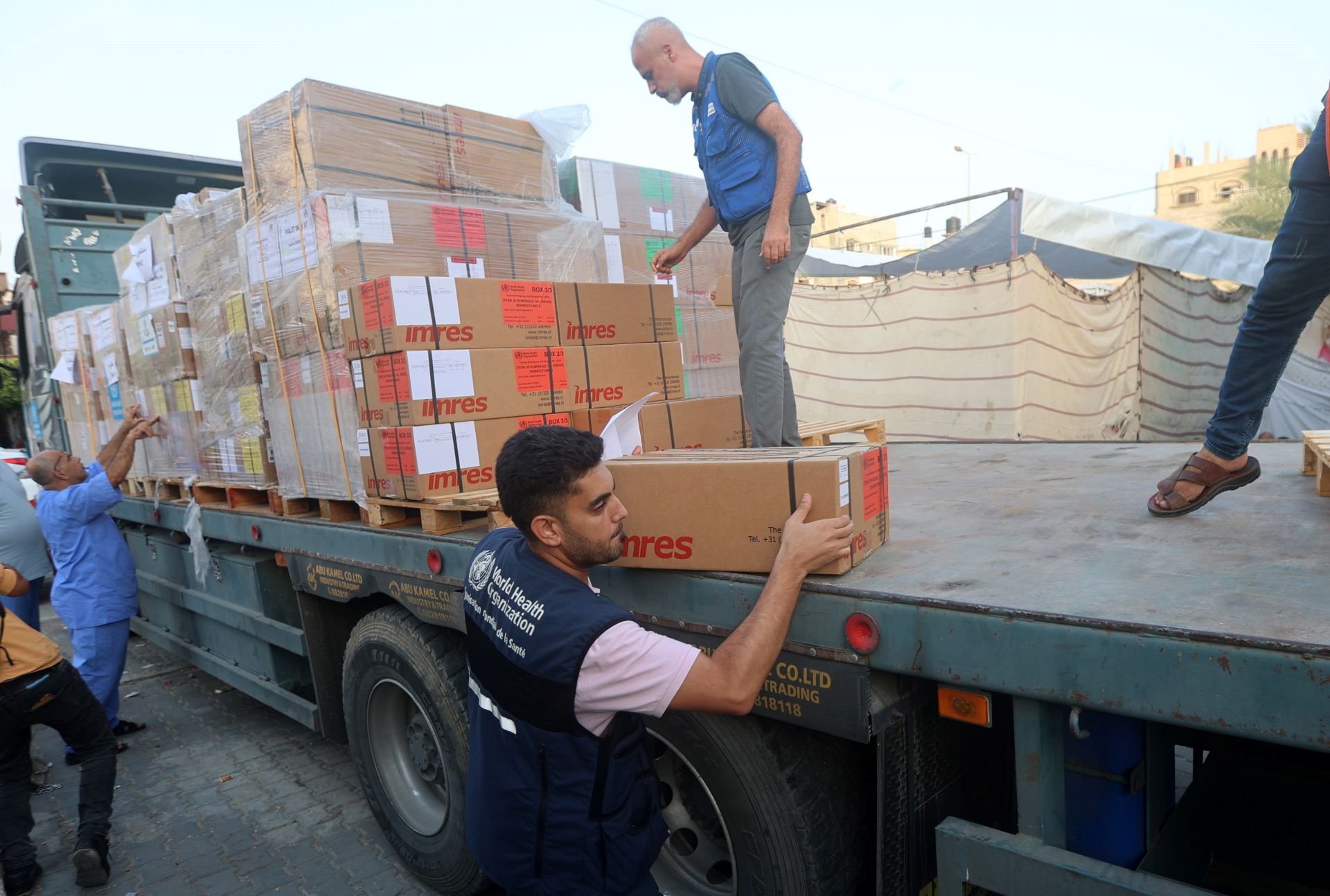Men unloading boxes of medical supplies from a large truck