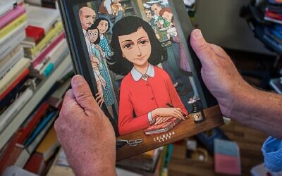A man holds a copy of the graphic novel version of "The Diary of Anne Frank," by Israeli writer-director Ari Folman and illustrator David Polonsky, in Paris on September 18, 2017. (Stringer/AFP via Getty Images via JTA)