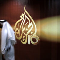 Illustrative: An employee of Al Jazeera walks past the channel's logo at its headquarters in Doha, Qatar, in 2006. (AP/Kamran Jebreili, File)