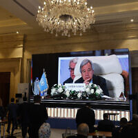 Journalists watch a large screen showing United Nations Secretary-General Antonio Guterres attending the International Peace Summit hosted by the Egyptian president in Cairo on October 21, 2023. (Khaled Desouki/AFP)