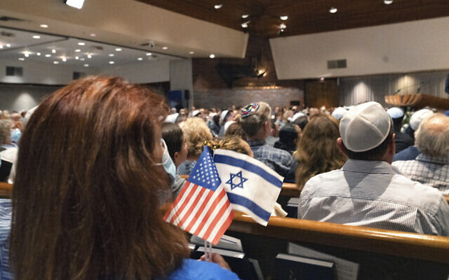 A woman holds an American flag and an Israeli flag during a 'Vigil for Israel,' at the Stephen Wise Temple in Los Angeles, October 8, 2023, to pray, sing and honor the memory of those killed in the recent massacre in Israel, and to pray for peace and the safe return of people kidnapped. (AP Photo/Richard Vogel)