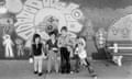 Children pose in front of a concrete wall decorated with a mural