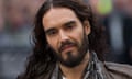 A close up of Russell Brand wearing a brown leather jacket