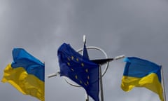 The Ukraine and EU flags in front of the Nato emblem in central Kyiv