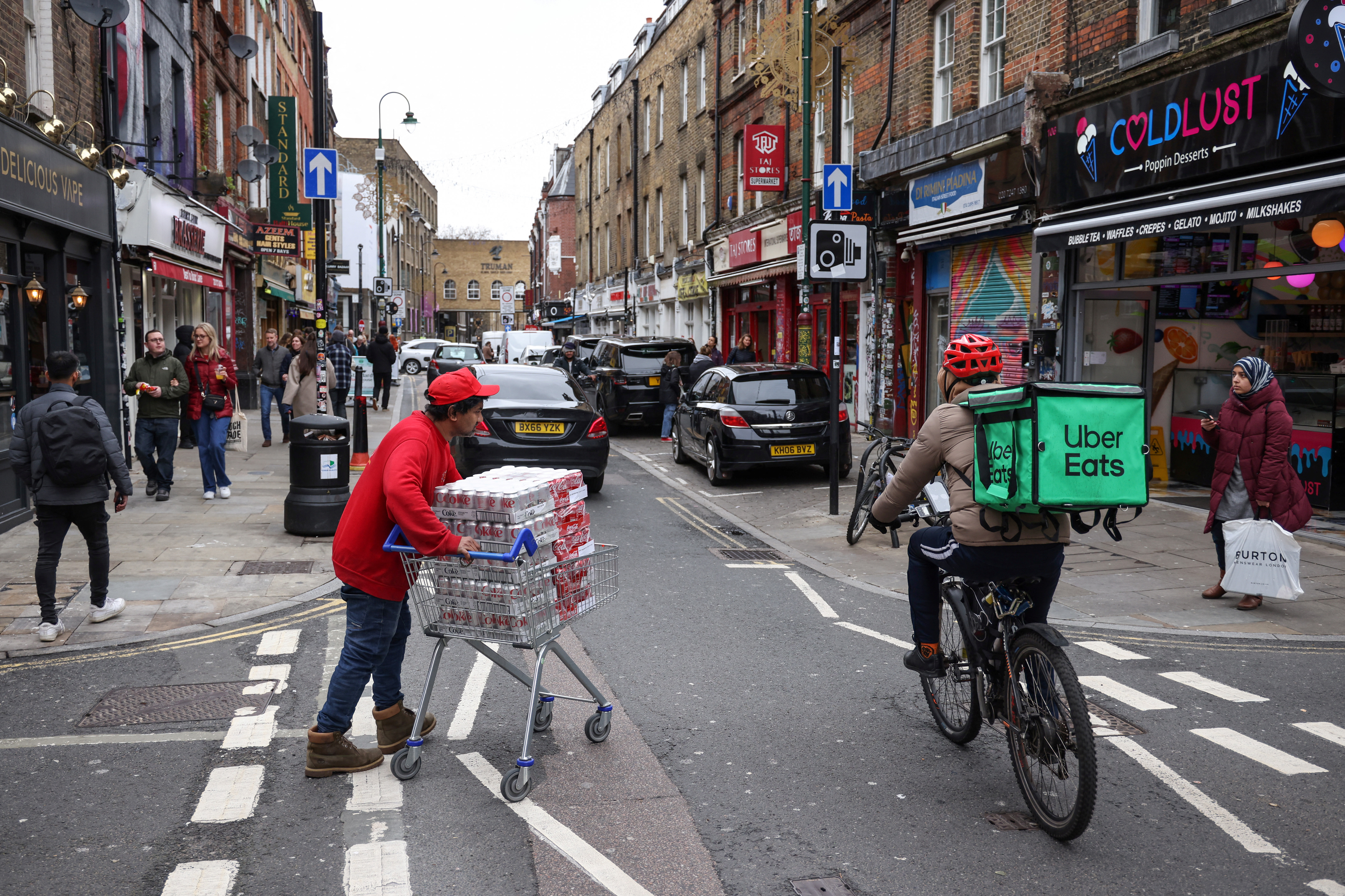 A man pushes a trolly of Coke cans in Brick Lane in London