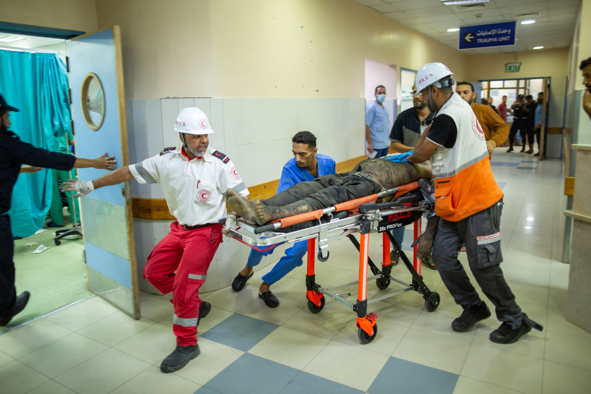 Injured man lying on a stretcher being rushed into a hospital room