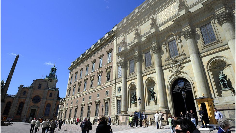 Tourists stroll by the Royal Castle in Stockholm