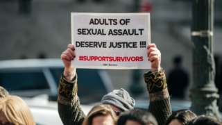 A demonstrator holds a sign overhead at a rally in support of the Adult Survivors Act on February 28, 2020 in New York City.